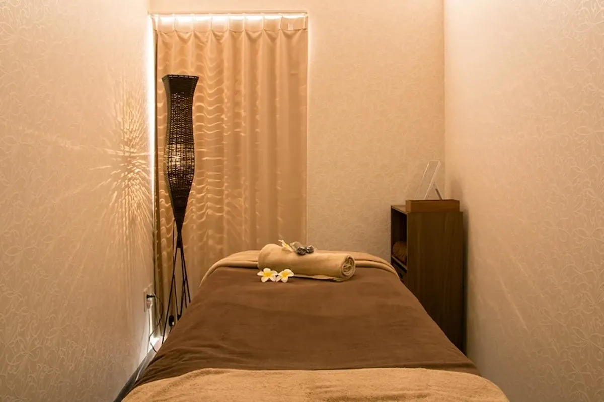 温かみのある、落ち着いた空間。マッサージベッドに置かれたタオルと花が、静寂と安らぎを演出しています。